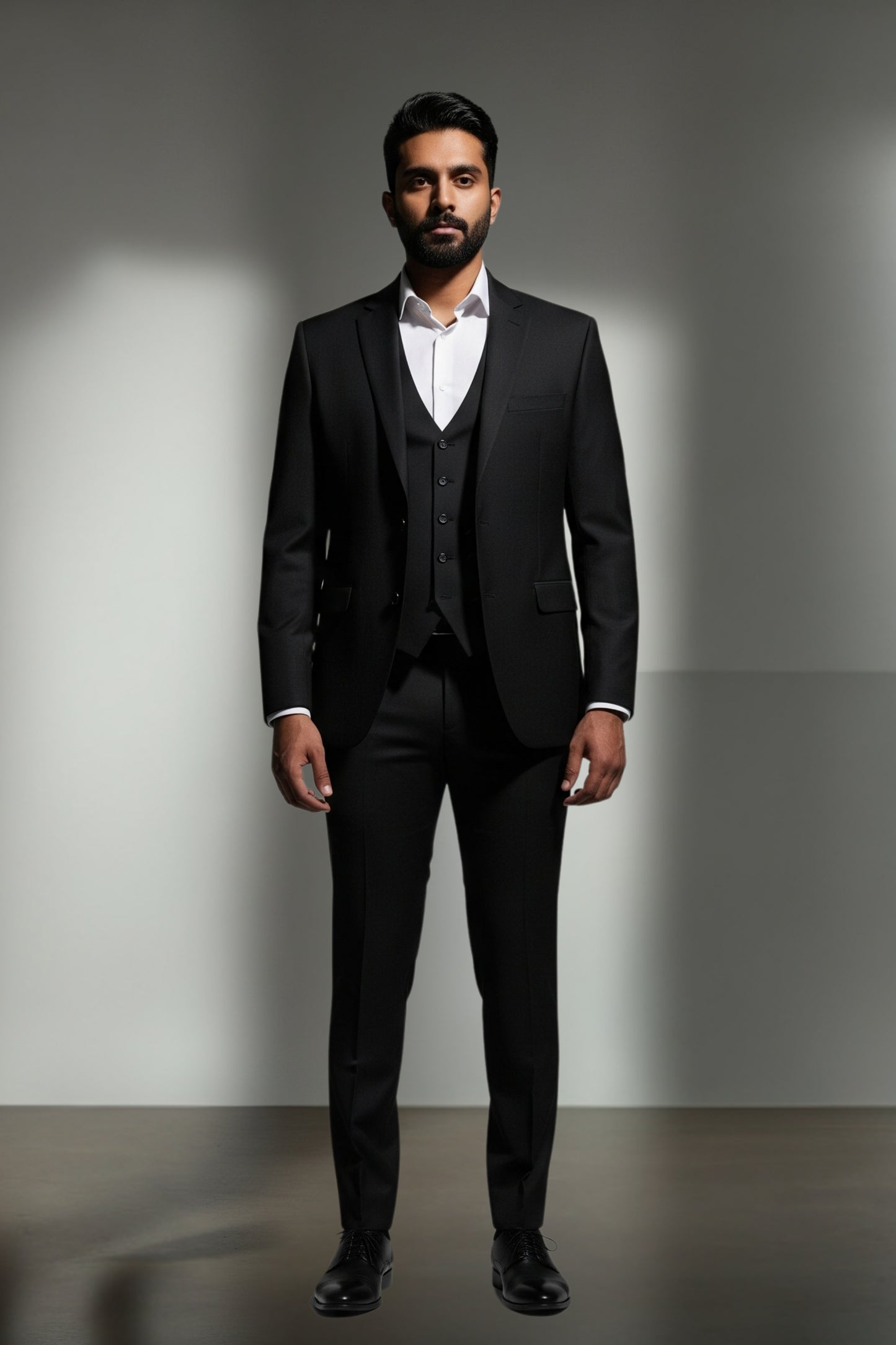 Man wearing a black suit with a white shirt against a gray background