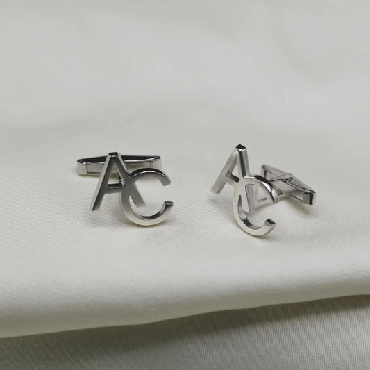 Silver cufflinks with 'AC' logo on a light gray background