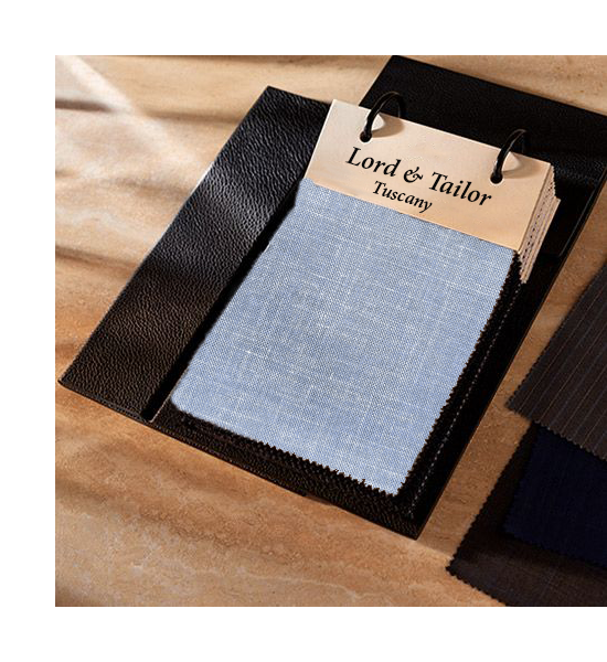 Fabric swatch with 'Lord & Tailor Tuscany' label on a wooden surface