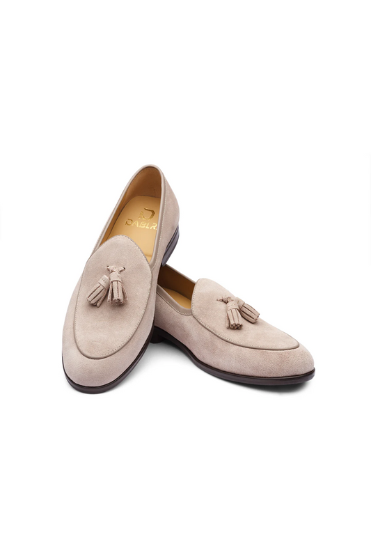 Pair of beige loafers with tassels on a white background