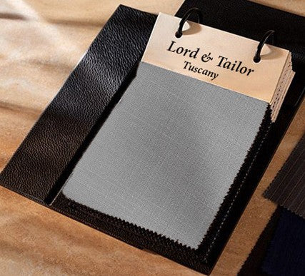 Gray fabric sample with 'Lord & Tailor Tuscany' label on a brown background