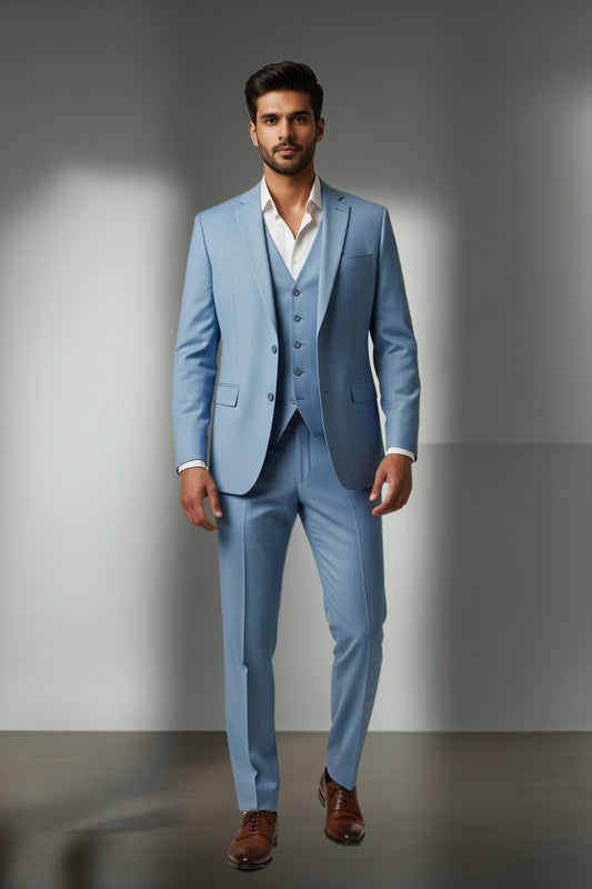 Man wearing a light blue suit with a white shirt and brown shoes on a gray background