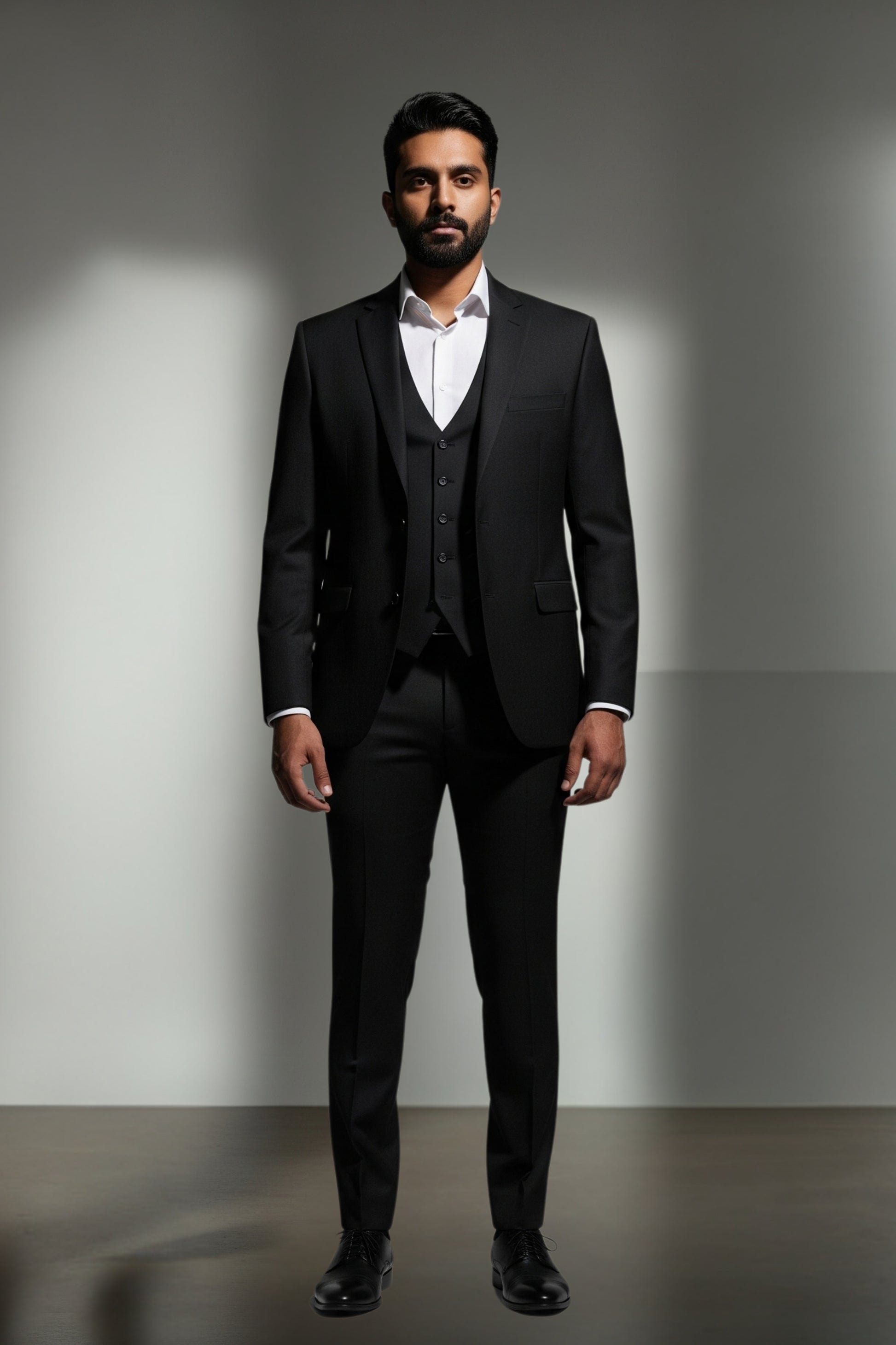 Man wearing a black suit with a white shirt against a gray background