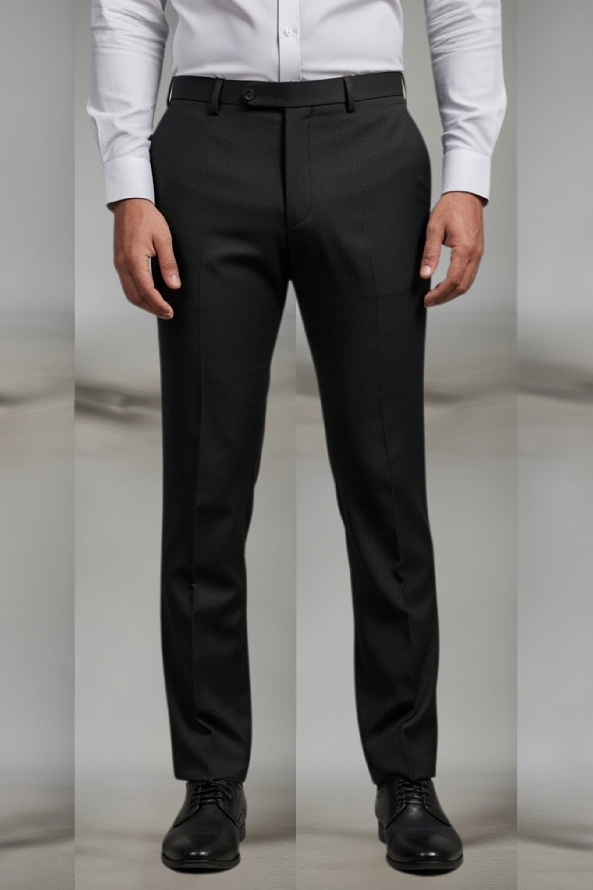 Black dress pants worn with a white shirt and black shoes on a neutral background