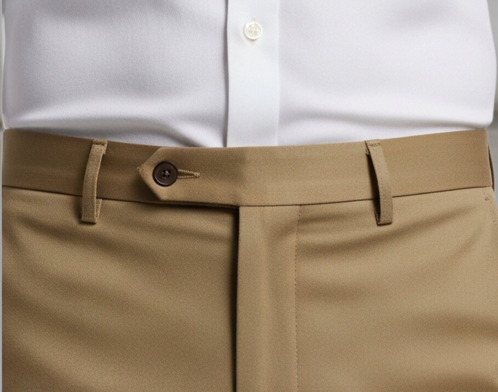 White shirt with a brown belt and beige pants against a gray background