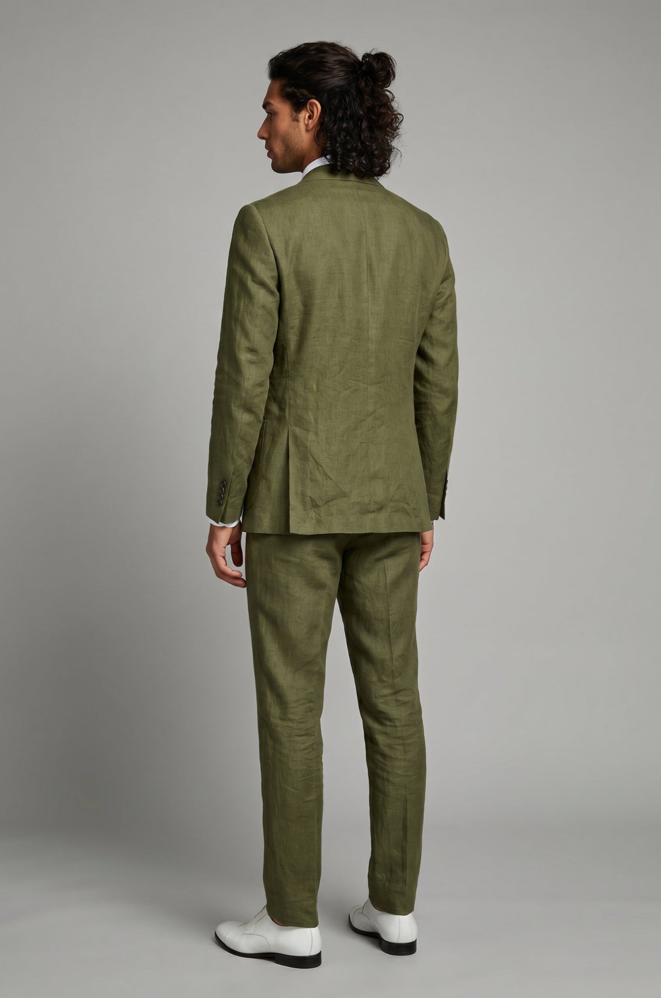 Person wearing a green suit standing against a plain background