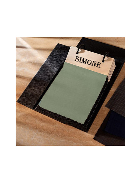 Green fabric sample with a 'SIMONE' label on a wooden surface