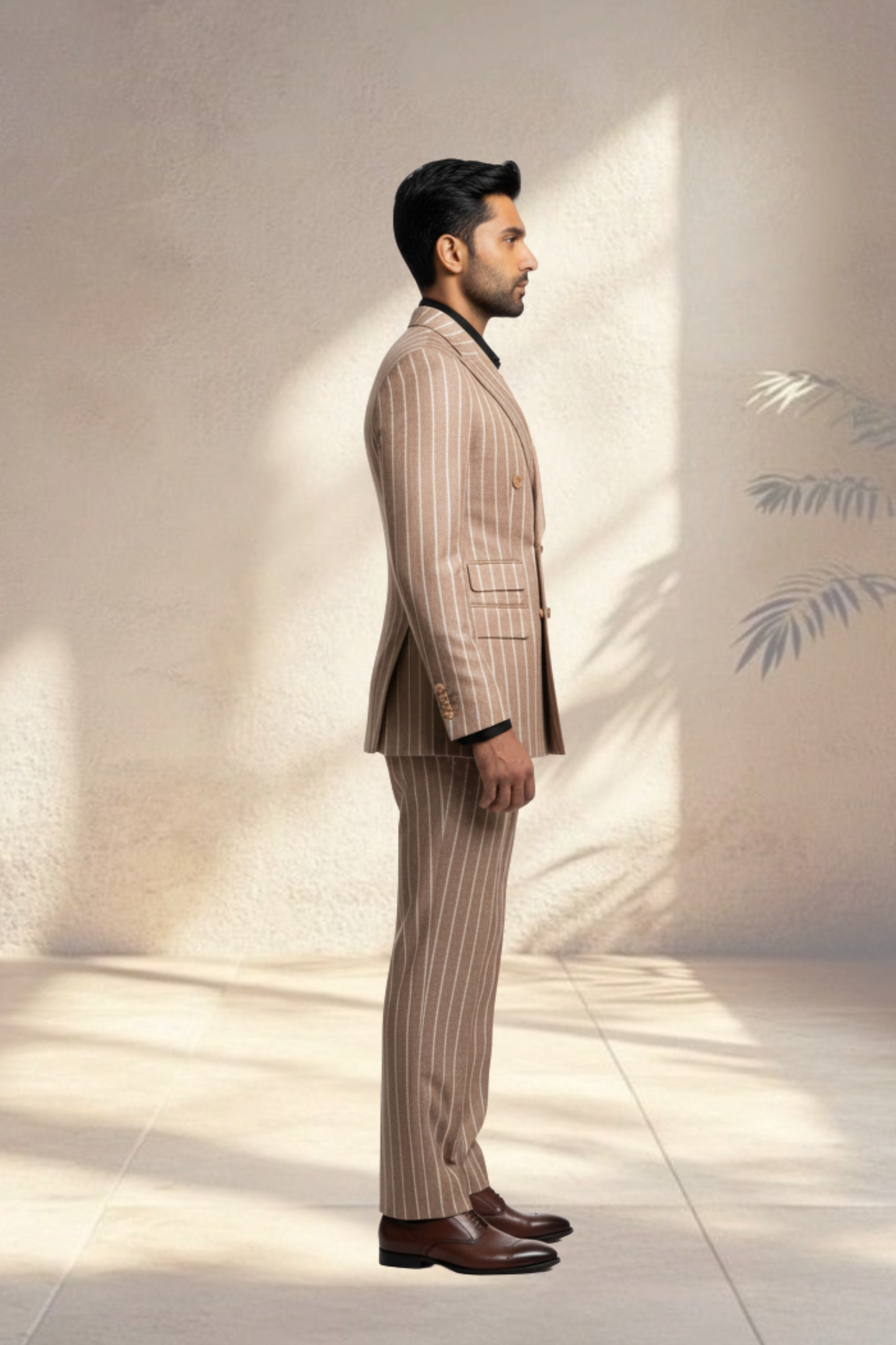 Man wearing a beige pinstripe suit standing against a light background