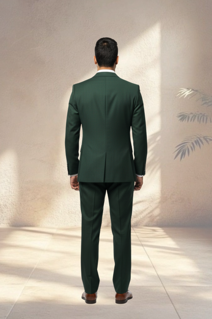 Man wearing a green suit standing against a light-colored wall with a subtle pattern.