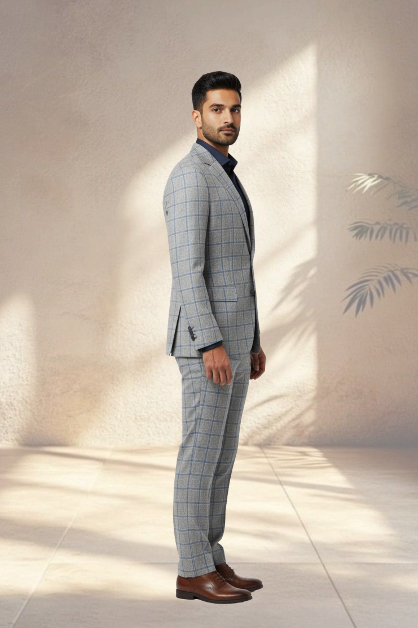 Man wearing a gray checkered suit with brown shoes against a light background