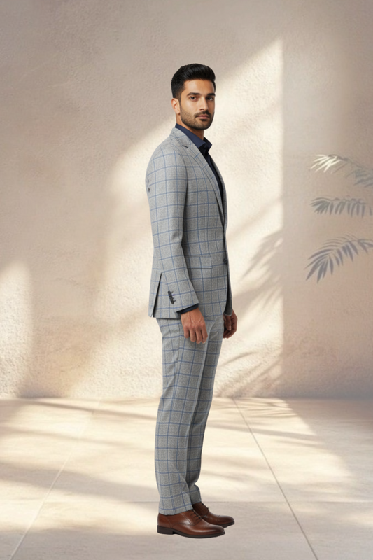 Man wearing a gray checkered suit with brown shoes against a light background