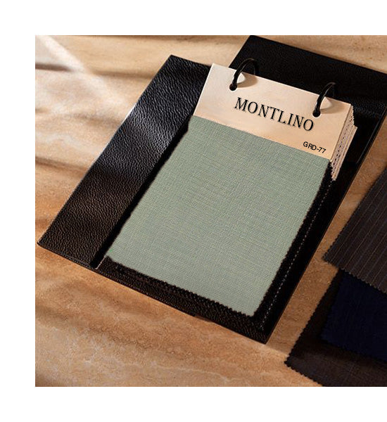 Fabric swatch with green material and 'Montlino' label on a wooden surface